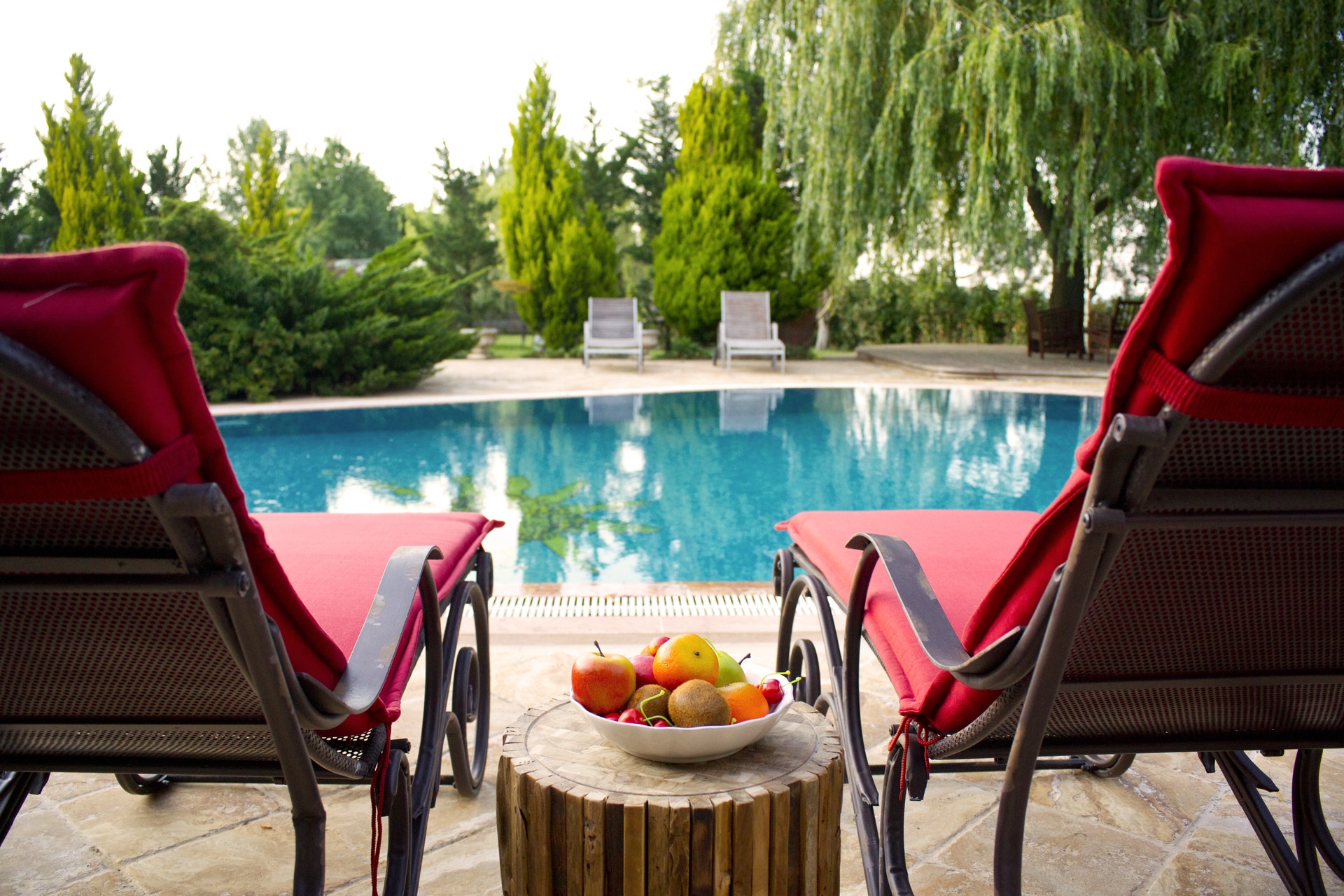 A backyard pool with lounge chairs at dusk